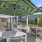 outdoor grilling and eating area with umbrella shaded tables and chairs